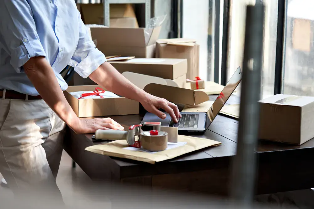 Female entrepreneur preparing packages while relying on storage in Singapore during relocation.