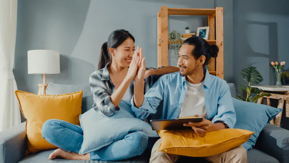 Happy Asian couple relaxing at home after decluttering their space with the help of cheap storage space for rent in Singapore.